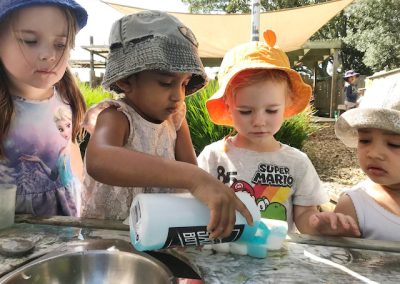 4 Children at daycare filling an ice cube tray with blue liquid